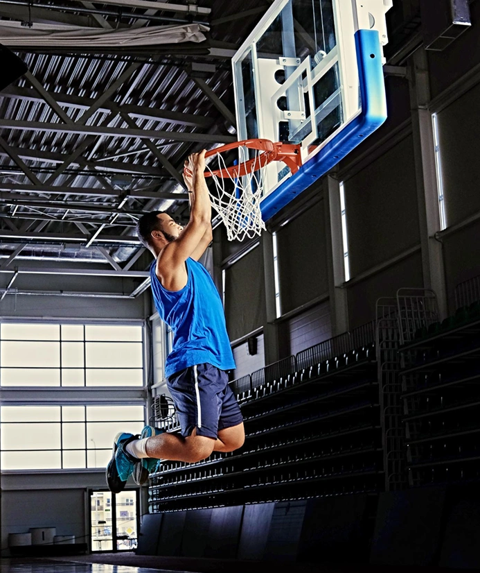 Jogador de basquetebol a praticar um afundanço durante uma sessão de treino num campo profissional.