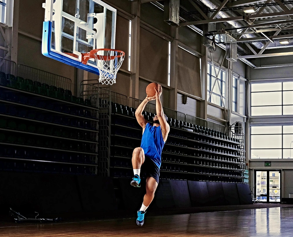 Atleta a conduzir em direção ao cesto para um layup durante o treino de basquetebol.