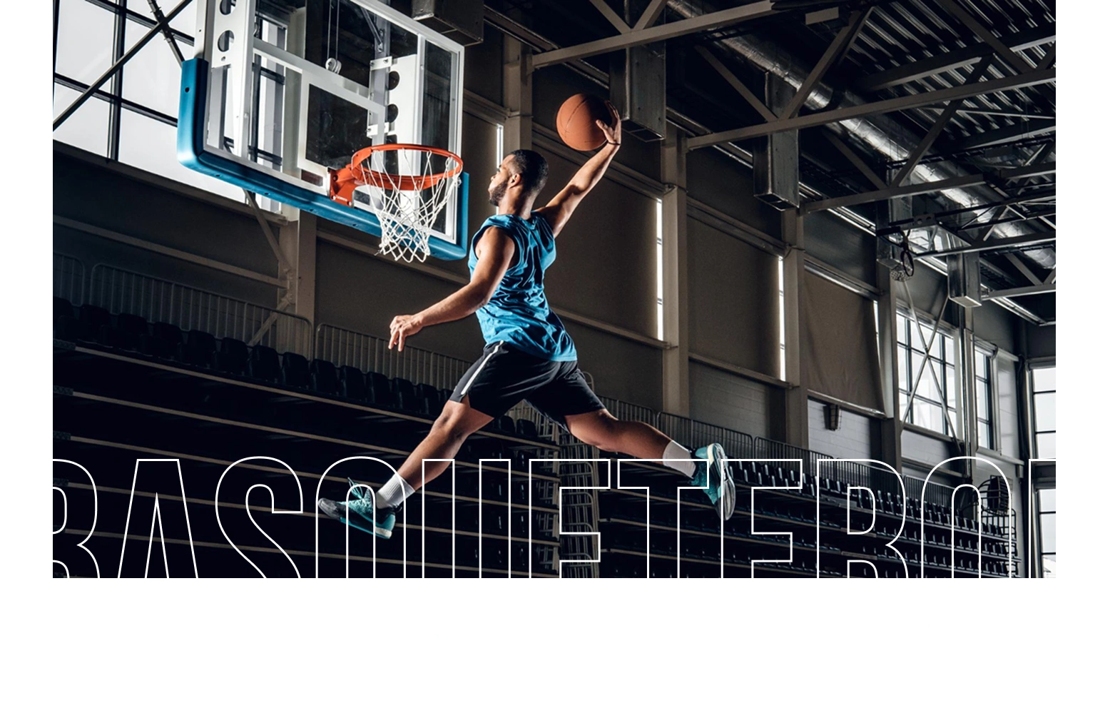 Jogador de basquetebol a voar pelo ar para um afundanço espetacular numa arena fechada, mostrando atletismo, potência e desempenho no basquetebol.